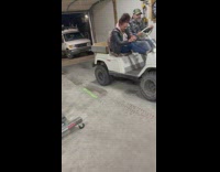 Guy and lady ride cart back and forth in garage 