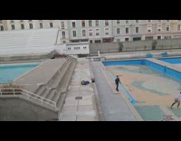 Three friends do parkour in empty pool deck, guy back flips and fails 