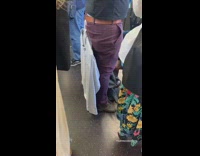 Guy uses back belt loop to hang clothes blue shirt on subway train