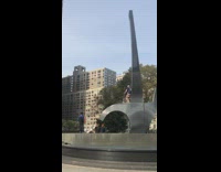 Guy stands on tall metal art sculpture with razor scooter
