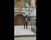 Man in full head mask nodding to himself on the sidewalk