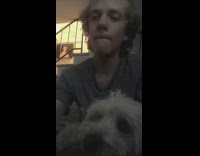 Dog watches grey shirt guy eat popcorn 