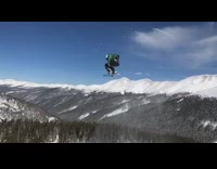 Snowboarder does two 360 spins off ramp, dog chases him