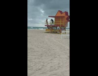 Girl poses on orange and red lifeguard station at beach