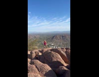 Woman flex arm muscles on mountain summit