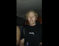 Blonde guy in black shirt with fiji water singing in car