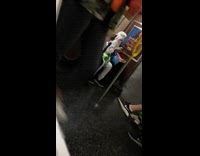 Woman in white wig face paint sits next to boy in halloween costume on subway train