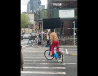 Man riding citibike balancing tv on head