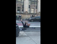 Man playing trombone with back on floor and feet in air