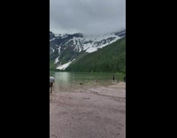 Woman violet dress stands on lake rock pictorial