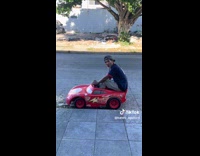 Man driving a lightning Mcqueen toy car 