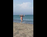 Grandpa red speedo jogs along beach shore 