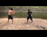 Two guys fight and reenact mortal kombat fight scene next to river