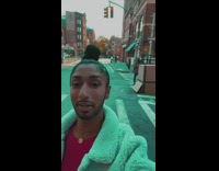 Guy in giant cardboard box walking in the middle of street in traffic