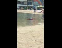 Guy takes picture Peppa the Pig on boogie board at beach