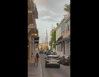 Woman in a beige dress poses at the sidewalk