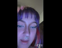 Girl with purple and pink hair in orange shirt with uneven breasts