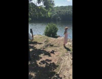 Woman beige dress yellow hat sunglasses lake