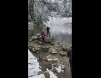 Woman beanie jacket stand rock snow lake