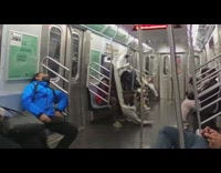 Guy sitting with car bumper on subway train