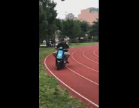 Father drives his daughter on a scooter through track field at the park on Fathers day