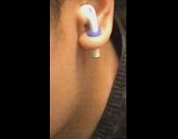 Guy listens to airpods while holding them in tunnel earring