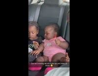 Two kids in the backseat sitting next to each other eating sweets