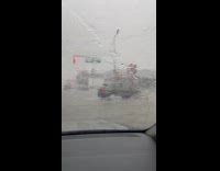 Cars drive through the flooded street during storm