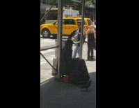 Man feeds pigeon that is sitting on top of his head, on the sidewalk