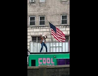 Man dances coffee truck roof beside flag