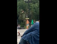 Shirtless guy blue shorts dances park hat 