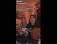 Girl playing guitar sings while friend claps  