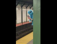 Person waits for subway with blue puppet 