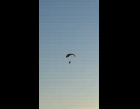 Paraglider fly over the beach during sunset