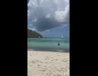 Woman blue hat orange jacket beach old man