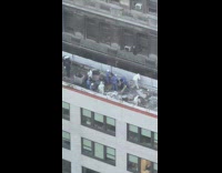 A bunch of workers on roof removing old roofing on a building 
