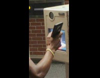 man in orange shirt 
talking to bank camera