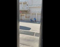 Guy rides a bellhop cart on the street 