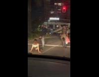 Woman sits middle of road while stoplight