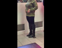 Woman standing in line touches her stomach