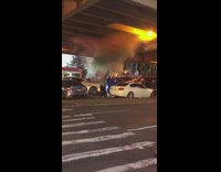 People gather under bridge smoke bombs cars