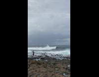 Man Takes Selfie on Rocky and Wavy Seashore