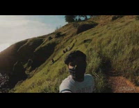 White shirt guy spins around grass hill 