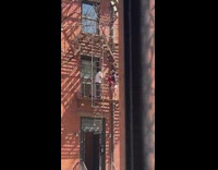 Couple fighting on fire escape throwing clothing