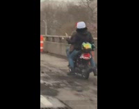 Two people on motorcycle ride on the sideline of freeway