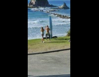 Man topless holds a surfboard by the beach