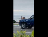 Shirtless guy jeans pocket street ocean overcast