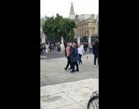 Woman in leather jacket white dress poses on the sidewalk