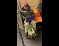 Old man uses laptop while riding subway