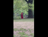 Woman in Red Dress Films Herself Next to Lake 